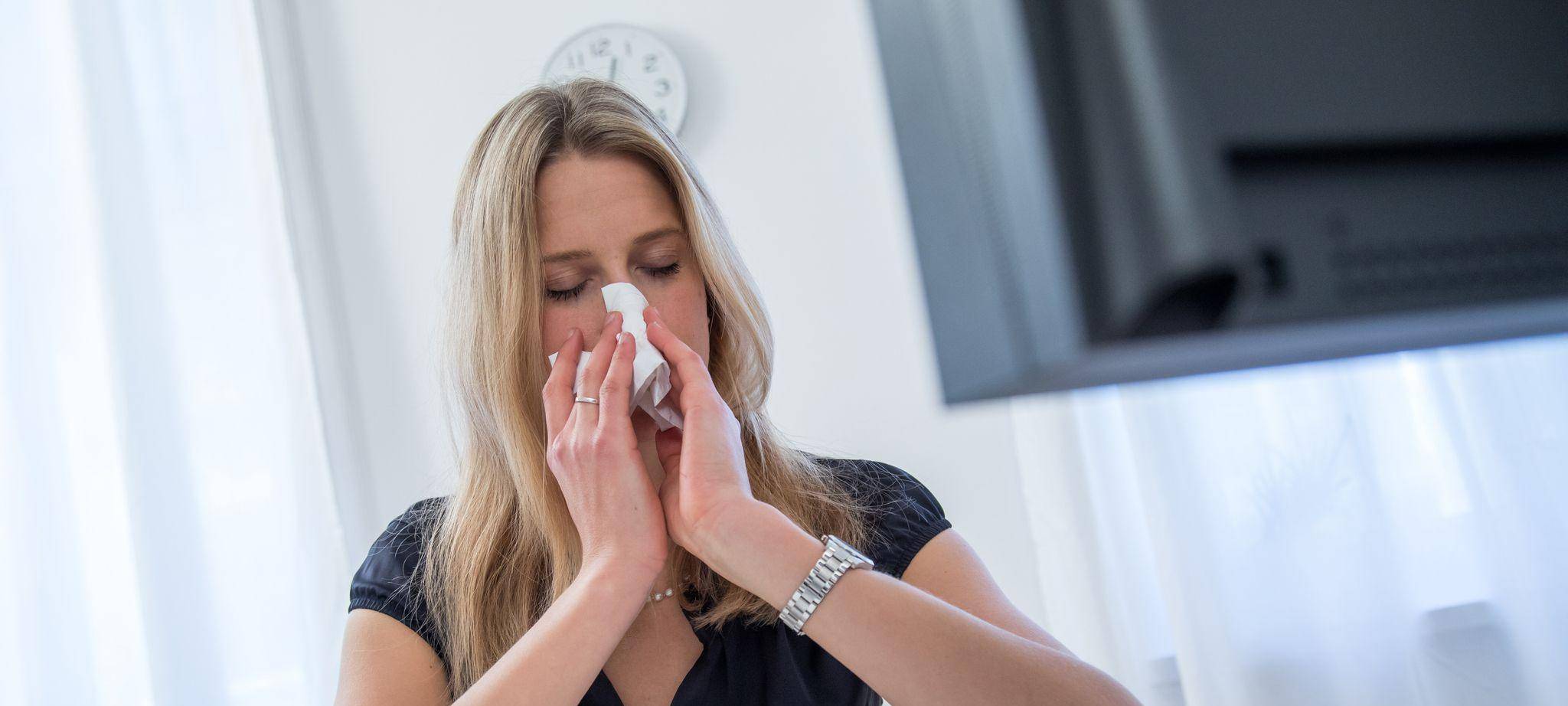 Frau sitzt erkältet vor ihrem Rechner zu Hause
