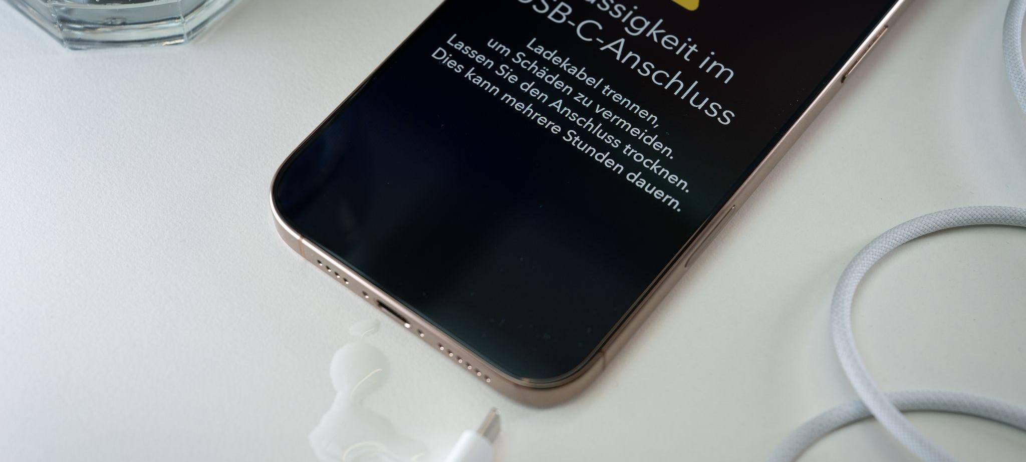 Ein iPhone mit einer Flüssigkeitswarnung und Wassertropfen