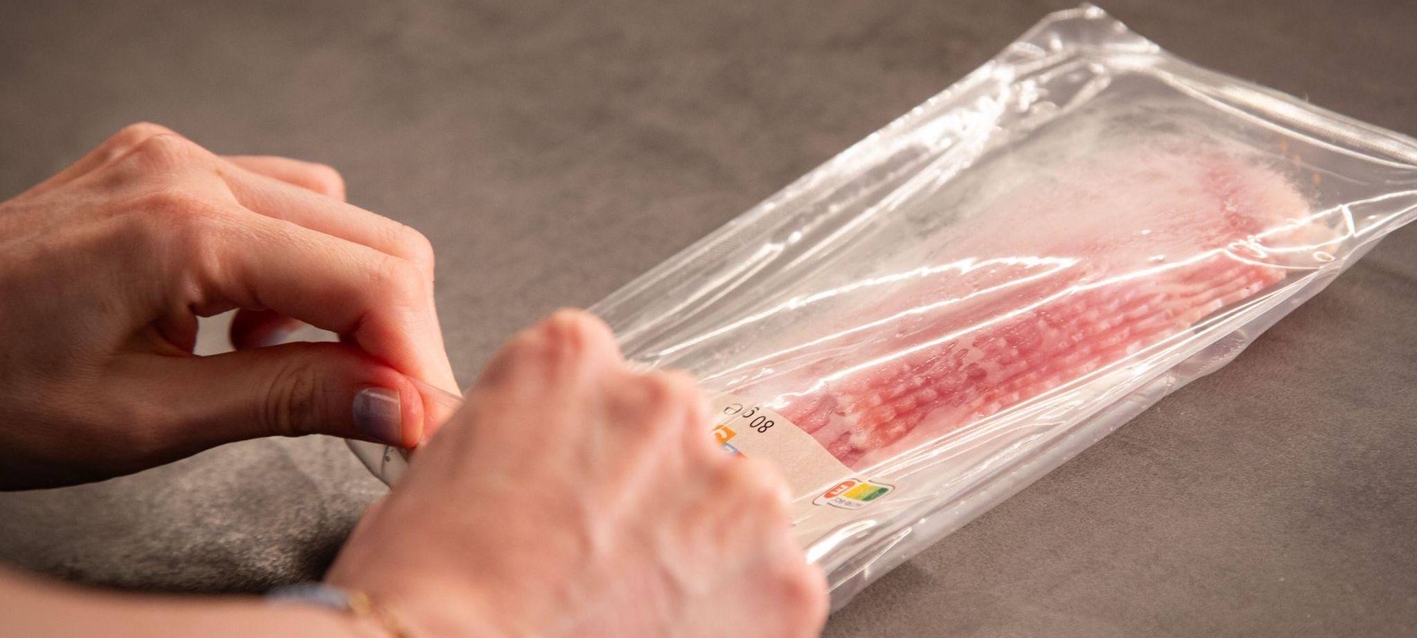 Eine Packung mit Bacon-Streifen wird geöffnet