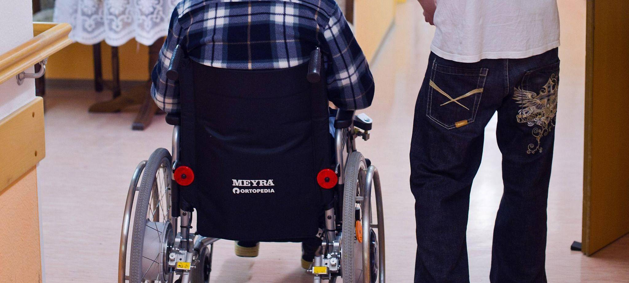 Freiwilligendienst: Ein junger Mann betreut einen älteren Mann