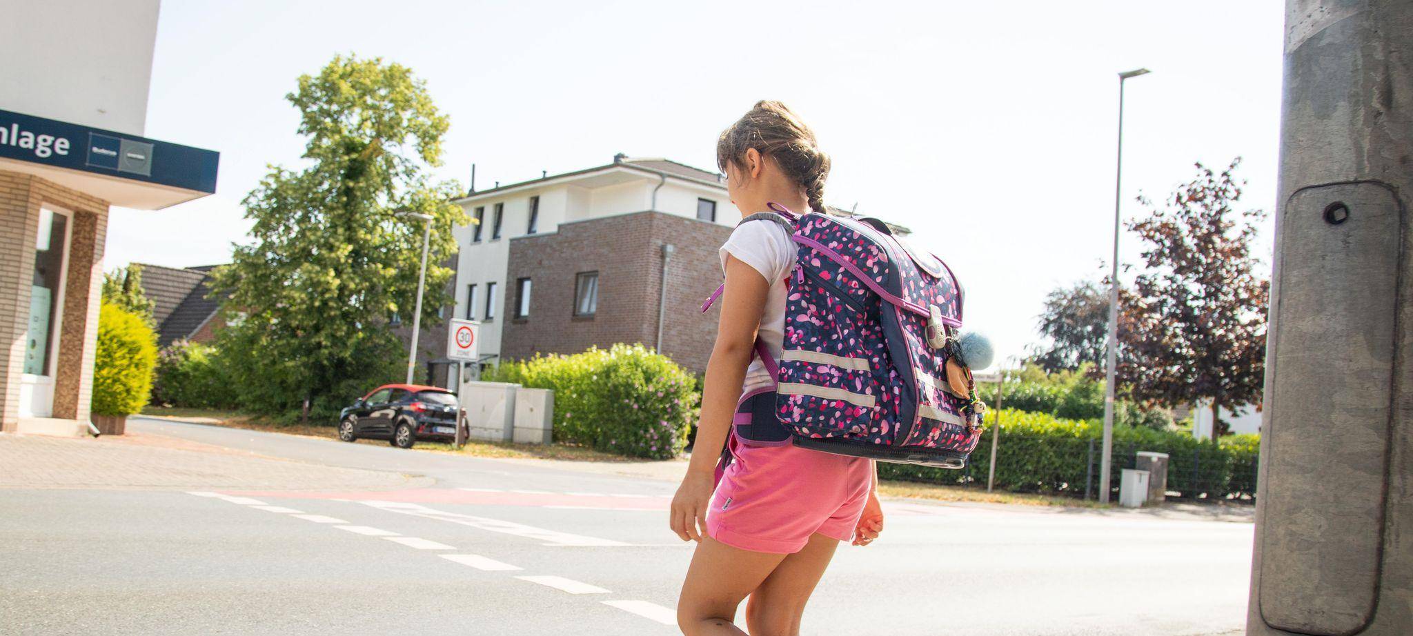 Ein Schulkind läuft mit Rucksack über die Straße